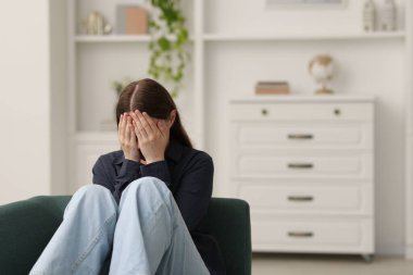 Evdeki kanepede ağlayan üzgün genç kadın, mesaj için yer.