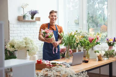 Dükkandaki ahşap masada çiçek buketi olan profesyonel bir çiçekçi.