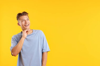 Hayaller gerçek oluyor. Pozitif genç adam sarı arka planda bir şeyler düşünüyor. Metin için boşluk