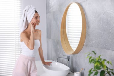 Hazırlanıyor. Evde genç bir kadın aynanın yanında dişlerini fırçalıyor.