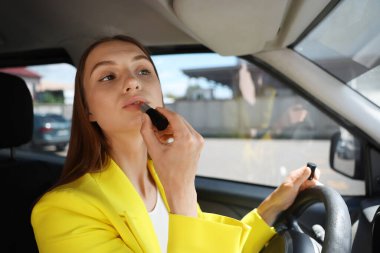 Hazırlanıyor. Genç bir kadın arabaya ruj sürüyor.