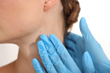 Doktor beyaz arka planda genç kadının benini inceliyor, yakın plan.