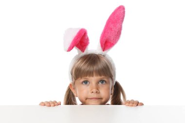 Tavşan kulaklı meraklı küçük kız beyaz arka planda masanın üstünden bakıyor.