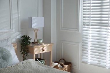 Yatağın içinde lamba ve diğer dekorlarla birlikte komodinin yanında.