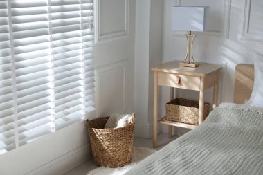 Yatağın yanında lamba olan komodin.