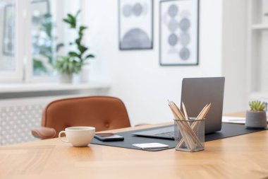 Modern dizüstü bilgisayarı ve ahşap masa üzerindeki kırtasiyesi olan şık bir iş yeri.