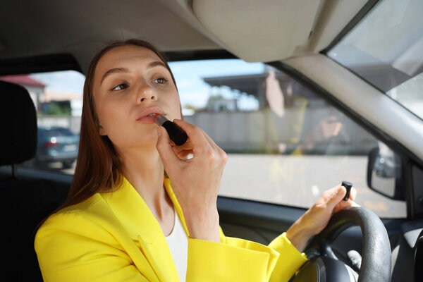 Готовлюсь. Молодая женщина наносит помаду в машине