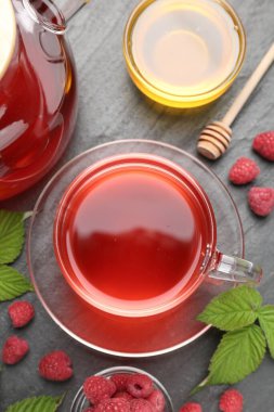 Cam fincanda Aromatik ahududu çayı, çaydanlık, böğürtlen, yeşil yapraklar ve bal siyah masada, düz yatıyordu.