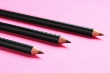 Pembe arka planda farklı kaş kalemleri, yakın plan.