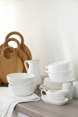 Mutfakta farklı beyaz bulaşık takımları ve tahta kesme tahtaları var.