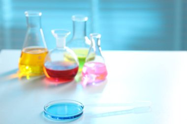 Işık masasında farklı numuneler bulunan laboratuvar camları, yakın plan. Metin için boşluk