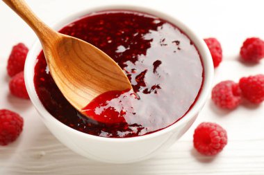 Beyaz masada kaseden kaşıkla ahududu reçeli alıp...