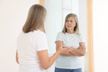 Üst düzey kadın aynada kendini ciddi bir şekilde yansıtıyor. Ruh Sağlığı