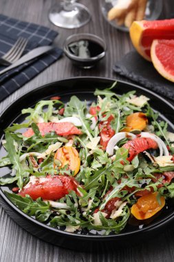 Lezzetli salata roka, peynir, greyfurt, sebze ve balzamik sosu koyu ahşap masada, yakın plan.