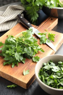 Taze aromalı maydanoz ve bıçak siyah ahşap masada, yakın plan.