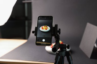 Stüdyoda akıllı telefonla lezzetli makarna çekmek, ekrana odaklanmak. Profesyonel yemek fotoğrafçılığı.