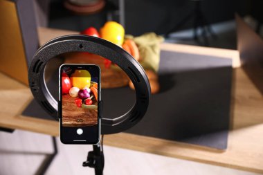 Stüdyoda akıllı telefonla sebze çekmek, ekrana odaklanmak. Profesyonel yemek fotoğrafçılığı.