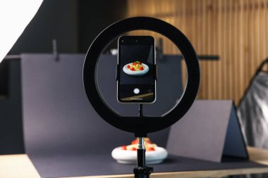 Stüdyoda akıllı telefonla lezzetli makarna çekmek, ekrana odaklanmak. Profesyonel yemek fotoğrafçılığı.