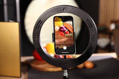 Stüdyoda akıllı telefonla sebze çekmek, ekrana odaklanmak. Profesyonel yemek fotoğrafçılığı.