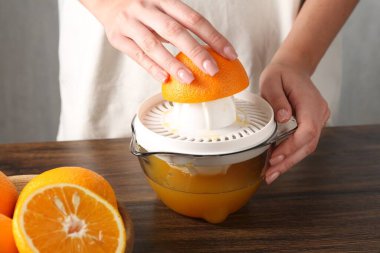 Meyve suyu. Tahta masada portakallı kadın meyve sıkacağı kullanıyor, yakın plan.