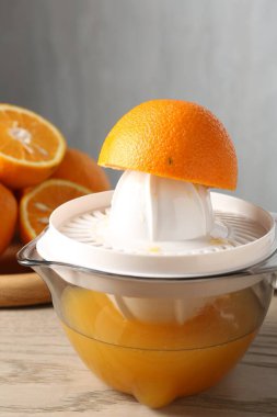 Meyve suyu. Meyve sıkacağı ve taze portakallar ahşap masada, yakın plan.