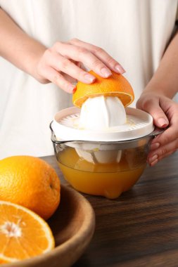 Meyve suyu. Tahta masada portakallı kadın meyve sıkacağı kullanıyor, yakın plan.