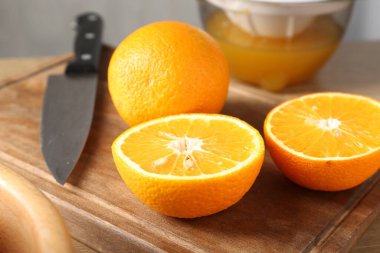 Meyve suyu. Taze portakallar, meyve sıkacağı ve bıçak masada, yakın plan.