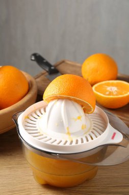 Meyve suyu. Meyve sıkacağı, taze portakal ve bıçak ahşap masada, yakın plan.