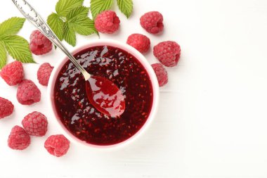 Tatlı ahududu reçeli kasede, böğürtlen ve yeşil yapraklar beyaz ahşap masada, düz yerde. Metin için boşluk