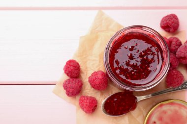 Cam kavanozda tatlı ahududu reçeli ve pembe ahşap masada böğürtlen. Metin için boşluk