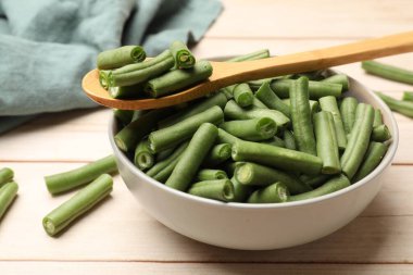 Taze bezelye kabukları kasede ve kaşıklar açık ahşap masada, yakın plan.