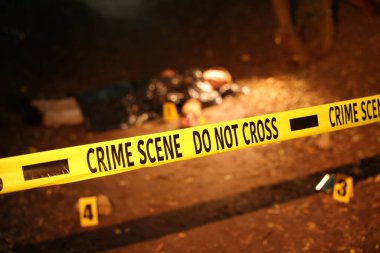 Adli tıp uzmanlığı. Cesedin bulunduğu suç mahalli ve dışarıdaki işaretler, polis bandına odaklan.