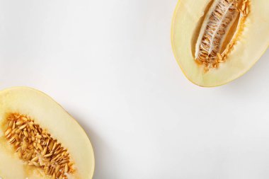 Beyaz arka planda olgun kavun yarımları, düz uzanmış. Metin için boşluk