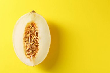 Sarı arka planda olgun kavunun yarısı, üst manzara. Metin için boşluk