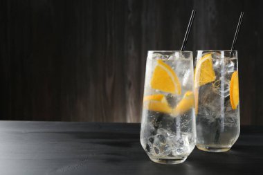 Portakal dilimli soda ve siyah ahşap masada buzlu bardaklar. Metin için boşluk