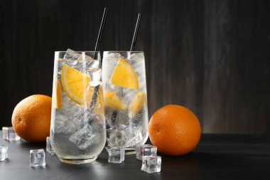 Siyah ahşap masada portakal dilimleri ve buz küpleriyle soda tazeliyorum. Metin için boşluk