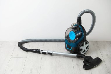 Beyaz duvarın yanında bir süpürge var.