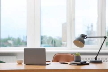 Modern dizüstü bilgisayarı ve ahşap masa üzerindeki kırtasiyesi olan şık bir iş yeri.