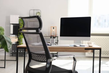 Ofisteki ahşap masa üzerinde modern bilgisayarı ve kırtasiyesi olan şık bir iş yeri.