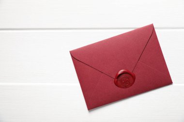 Beyaz ahşap masa üzerinde balmumu mühür olan zarf, üst manzara. Metin için boşluk