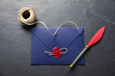 Balmumu mühür, sicim ve dolma kalemle kaplanmış siyah masa, düz uzanmış.