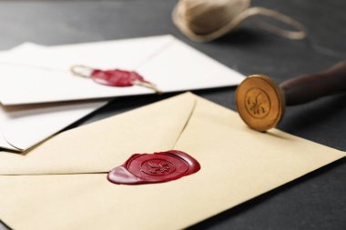 Balmumu mühürlü zarflar ve siyah masa üzerinde damga, yakın çekim