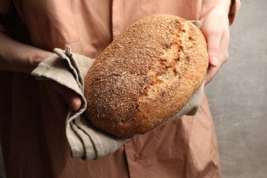 Gri arka planda taze ekmeği olan kadın, yakın plan.