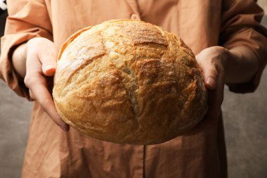 Gri arka planda taze ekmeği olan kadın, yakın plan.