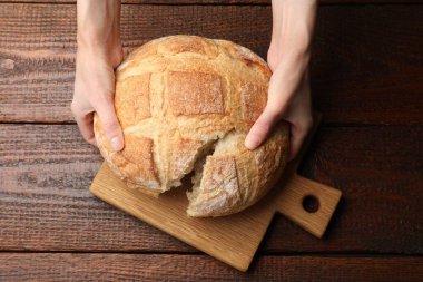 Ahşap masada taze ekmek paylaşan bir kadın.