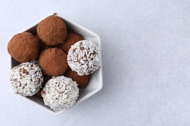 Beyaz masadaki kasede kakao tozu ve hindistan cevizi gevreği bulunan nefis ev yapımı şekerler. Metin için boşluk