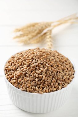 Kasede buğday taneleri ve beyaz masada çiviler, yakın plan.