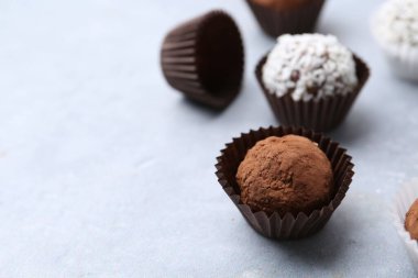 Açık gri masada kakao tozu ve hindistan cevizi gevreği ile nefis ev yapımı şekerler, yakın plan. Metin için boşluk