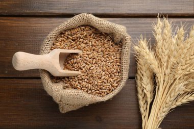 Çuval bezi torbasında buğday taneleri, tahta masada kepçeler ve çiviler.