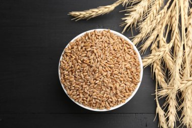 Kasede buğday taneleri ve siyah ahşap masada çivili çubuklar. Metin için boşluk